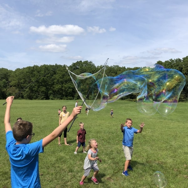 First Congo church children playing with huge bubble machines in field