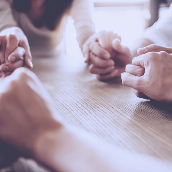 Pairs of hands holding each other while praying