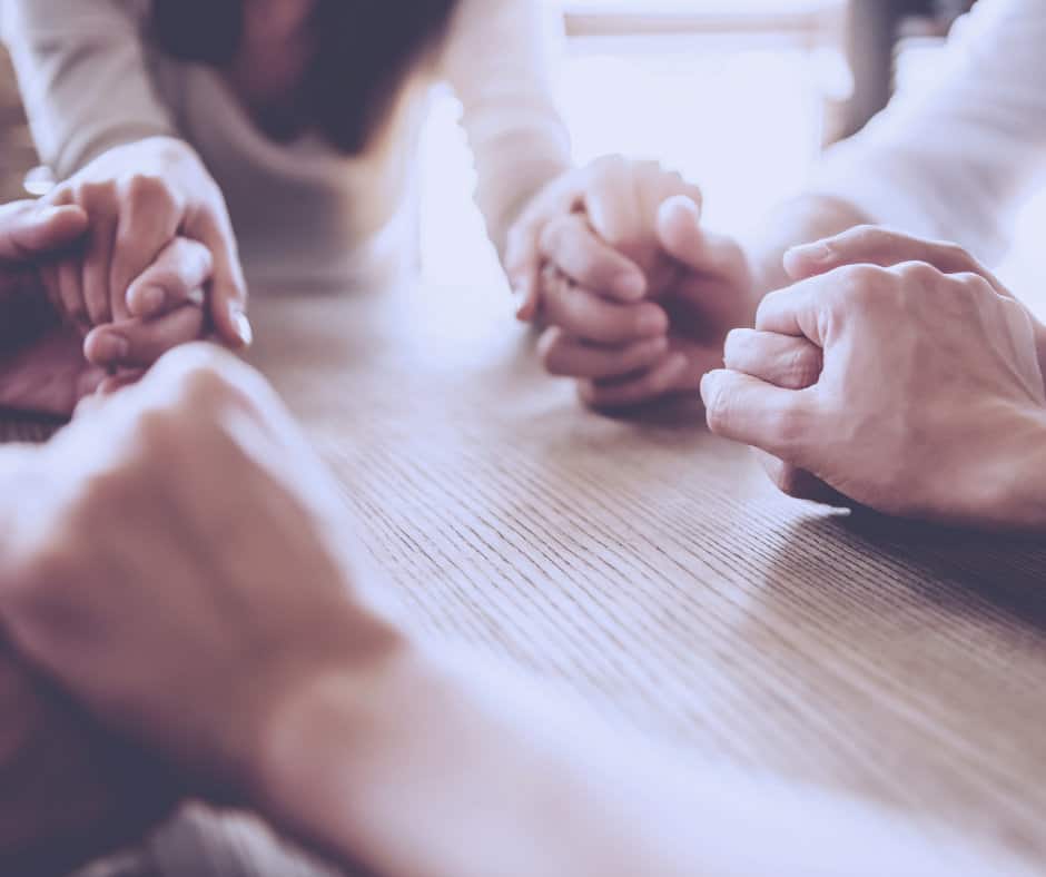 Pairs of hands holding each other while praying