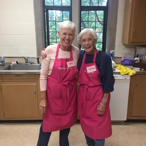 Two happy woman hugging in a kitchen