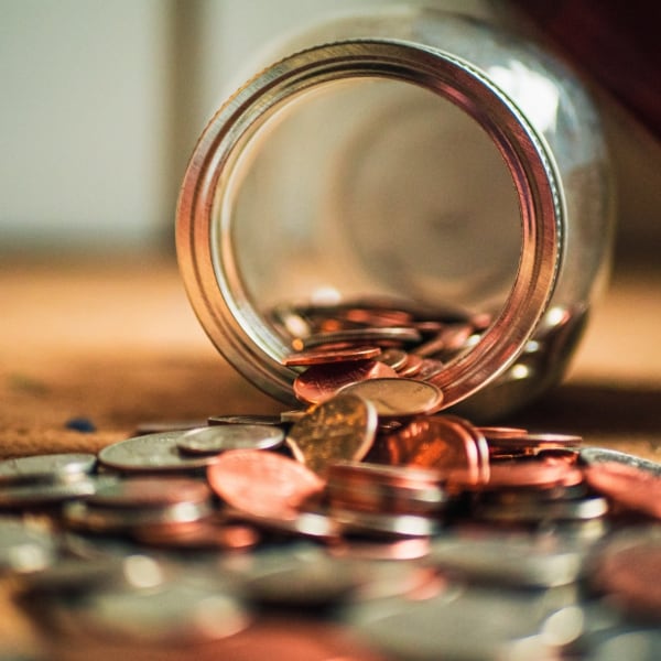 A jar of coins spilled on a table