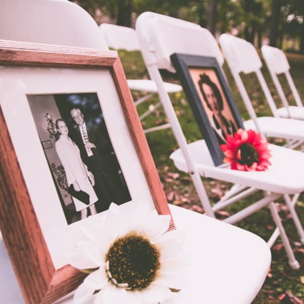 Family photos with flowers on chairs at a memorial service