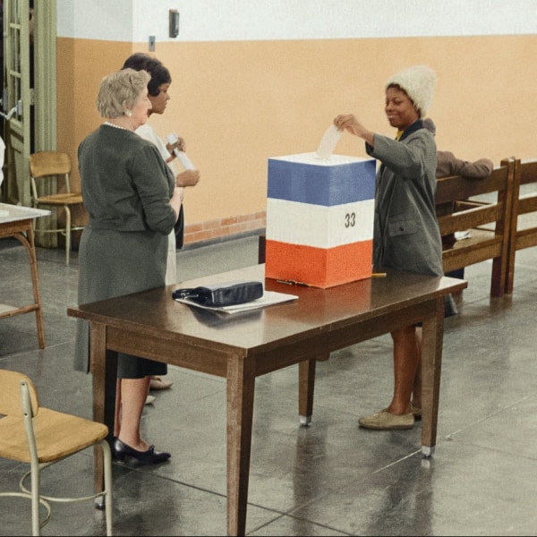 A woman casting her vote at a ballot booth