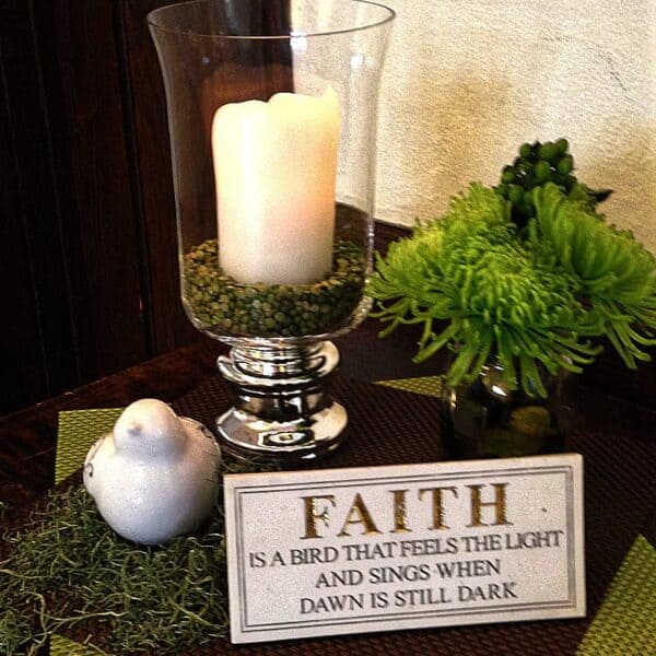 A candle on a table with a Faith card