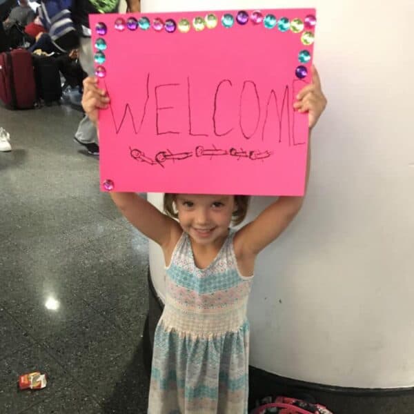 Girl holding a pink welcome sign for First Congo visitors